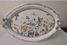 a white tray with flowers and butterflies painted on the side is sitting on a table