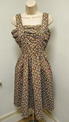 This is a cotton handmade sun dress that we recently obtained from an TX estate sale. The garment dates to the 1940s/ 1950s. The fabric is a good quality medium weight material in a novelty print of yellow roses and green shamrocks. Colors are Yellow, Blue and Green on an Aubergine background. COLORS MAY VARY BASED ON YOUR MONITOR The garment is sleeveless and the bodice is ruched in front as well as the sides. The dress zips at the side seam. The dress is fit and flare style: fitted at the wais Vintage Fitted Cotton Sundress, Fitted Vintage Cotton Sundress, Retro Cotton Sundress With Floral Print, Retro Floral Print Cotton Sundress, Dark Blue Dress, Body Form, Dress Purchase, Novelty Print, Sun Dress