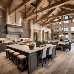 a large open concept kitchen and dining room with wood beams on the ceiling, hardwood flooring