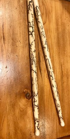 two white candles sitting on top of a wooden table