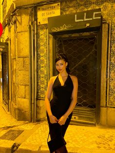 a woman in a black dress standing on the street