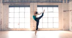 a woman is doing a ballet move in an empty room with windows and brick walls