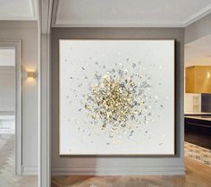 a large white and gold painting hanging on the wall in a room with hardwood floors