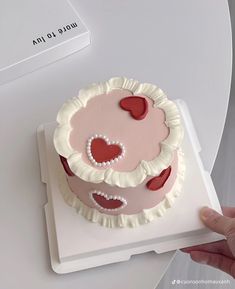 a hand is holding up a cake with hearts on it