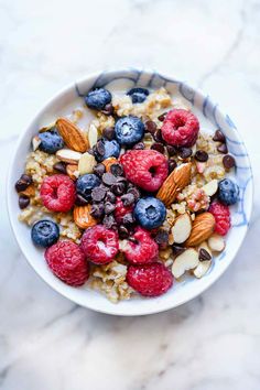 a bowl filled with oatmeal, raspberries and almonds on top of a marble counter