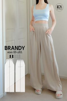 a woman standing in front of a door with her hands on her hips wearing wide legged pants