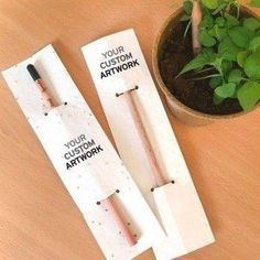 two plant markers sitting on top of a wooden table next to a potted plant