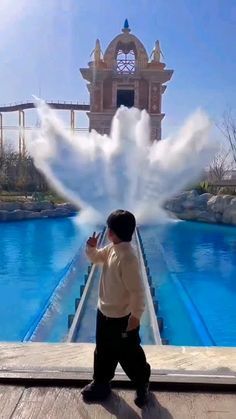 a young boy standing in front of a water fountain