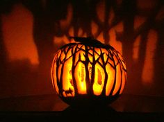 a carved pumpkin sitting on top of a table in front of a shadow cast wall