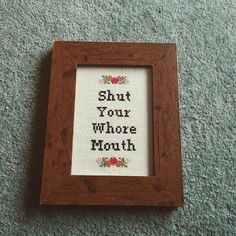 a cross - stitch picture frame with the words shut your whole mouth on it sitting on carpet