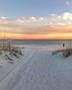 there is a person walking on the beach at sunset