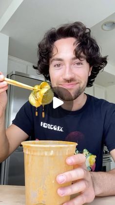 a man eating food from a yellow cup