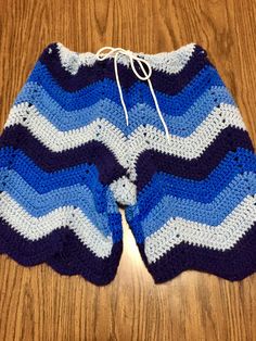 a blue and white crocheted shorts on top of a wooden floor