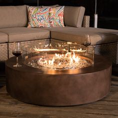 a fire pit sitting on top of a wooden floor next to a couch and table