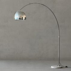 a floor lamp with a chrome finish on the base and a round glass shade over it