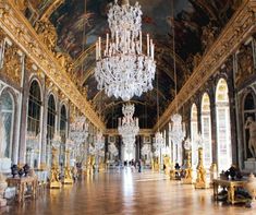 an ornate hall with chandeliers and paintings on the walls