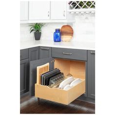 an open drawer in the middle of a kitchen with utensils and cutting boards