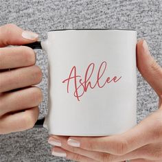 a woman holding a white coffee mug with the word able on it in red ink