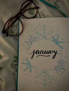 an open book with the word january written on it next to glasses and a pair of eyeglasses