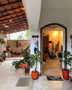 the inside of a house with potted plants and hammocks hanging from the ceiling