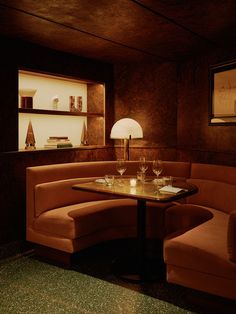 a corner table with two wine glasses on it in a dimly lit room next to a book shelf