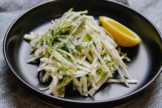 a black plate topped with shredded cheese and a lemon wedge