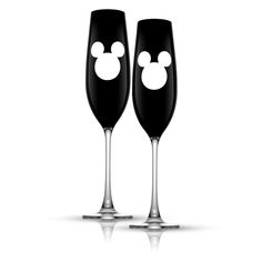 two black wine glasses with white mickey mouse heads on the bottom and one is empty