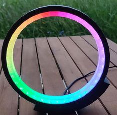 a multicolored light sitting on top of a wooden table next to green grass