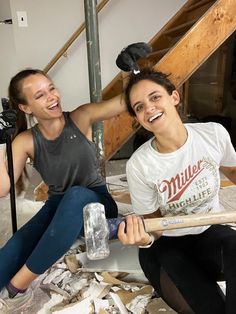 two women are sitting on the floor and one has a baseball bat in her hand