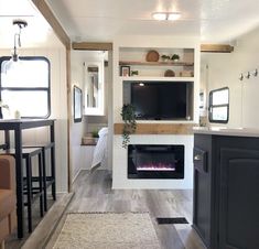 a living room and kitchen area in a mobile home with an entertainment center on the wall