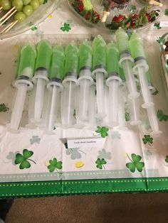 several plastic bottles filled with green liquid sitting on top of a table next to plates of food