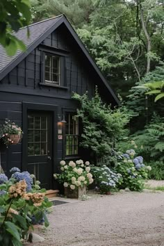 a black house surrounded by trees and flowers