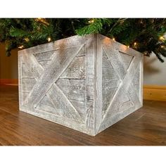 a wooden box sitting on top of a hard wood floor next to a christmas tree