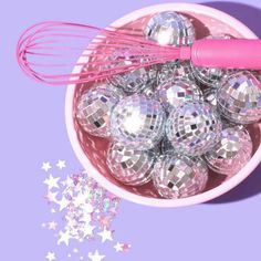 a bowl filled with disco balls and a whisk on top of it next to stars