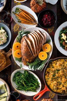 a table full of food including bread, orange slices and other foods on plates with utensils