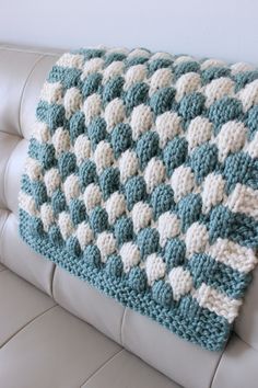 a blue and white crocheted blanket sitting on top of a couch