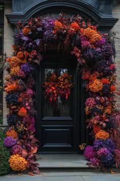 a black door surrounded by purple and orange flowers