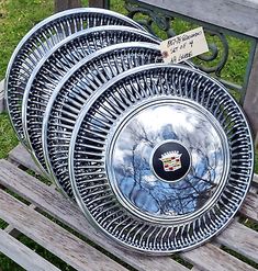 four metal plates sitting on top of a wooden bench