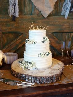 a white wedding cake sitting on top of a wooden table next to a knife and fork