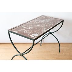 a small table with a marble top and metal legs on a wooden floor in front of a white wall