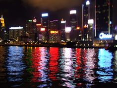 the city lights shine brightly in the water at night time as it reflects on the surface of the water