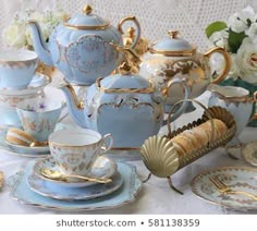 a table topped with lots of blue and white dishes covered in gold trimmings