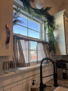 the kitchen window is decorated with greenery and hanging from it's trimmings