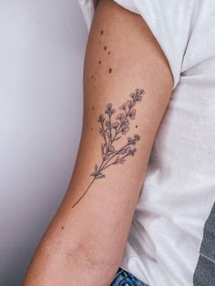 a woman's arm with a tattoo on it that has flowers growing out of it