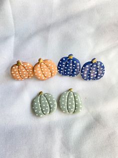 four different colored pumpkins sitting on top of a white cloth covered tablecloth with polka dots