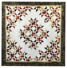 a quilt made with red, yellow and black triangles on white fabric is displayed in front of a wooden frame