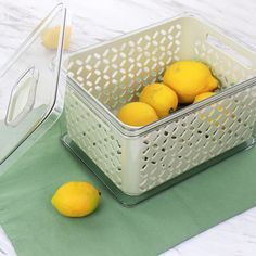 two lemons in a plastic basket next to a glass container with a lid on it