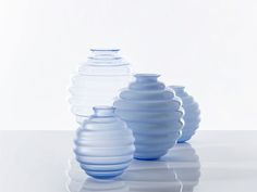 three blue vases sitting next to each other on a white surface with reflections in the water