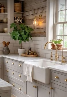 a kitchen with white cabinets and gold knobs on the cupboards, an island sink and brass faucets