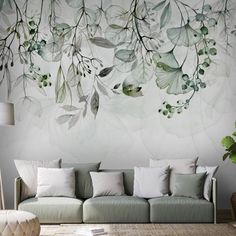 a living room scene with focus on the couch and wall mural behind it that has green leaves